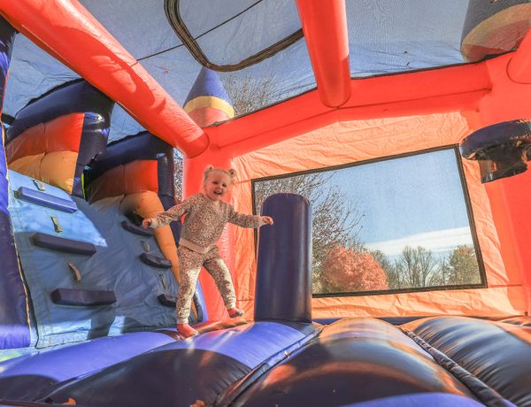 A child plays inside a colorful inflatable bounce house.